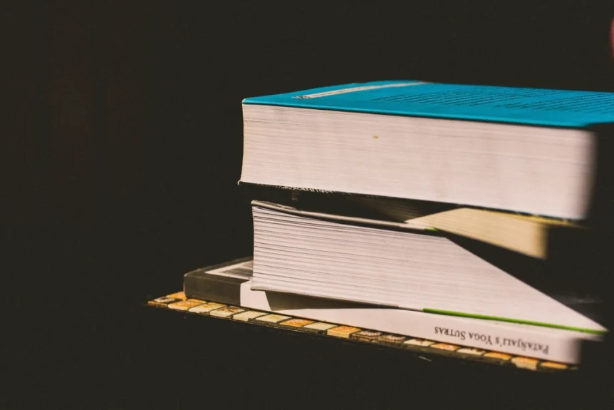 A small stack of books lit by sunlight against a dark background