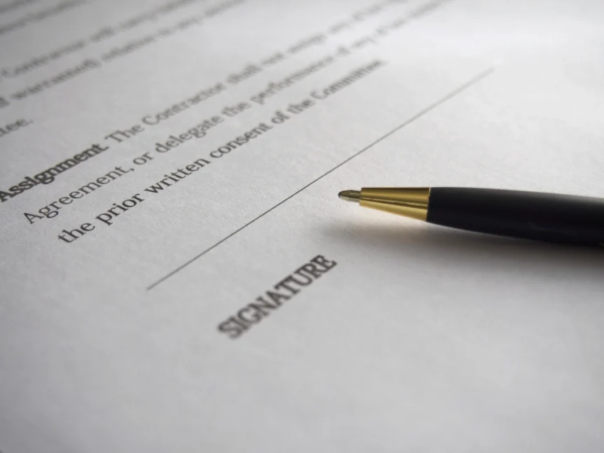 Pen resting on a printed agreement next to a signature line