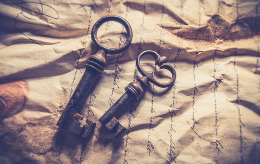 Two antique keys lying on crumpled handwritten paper