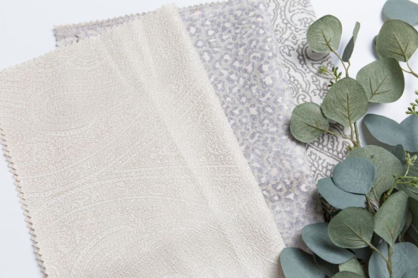 Patterned fabric swatches with eucalyptus sprigs on a white surface
