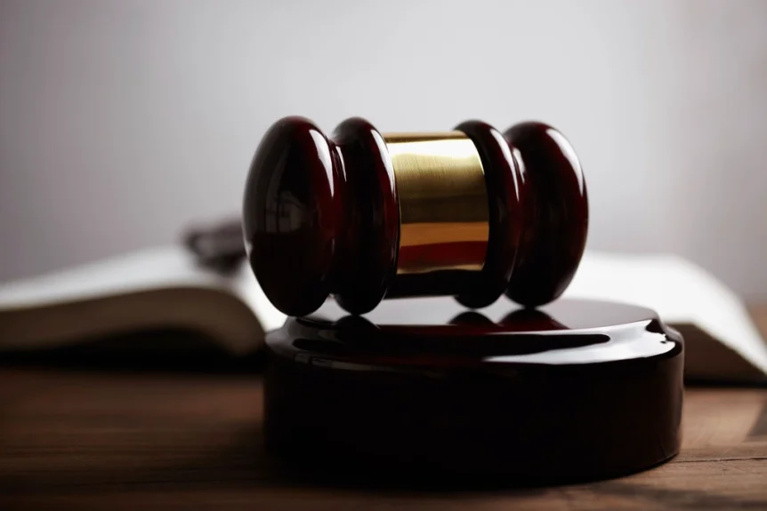 Wooden gavel on its sound block in front of an open book