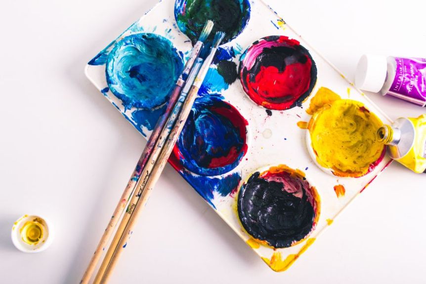 Paint palette with bright colors and brushes
