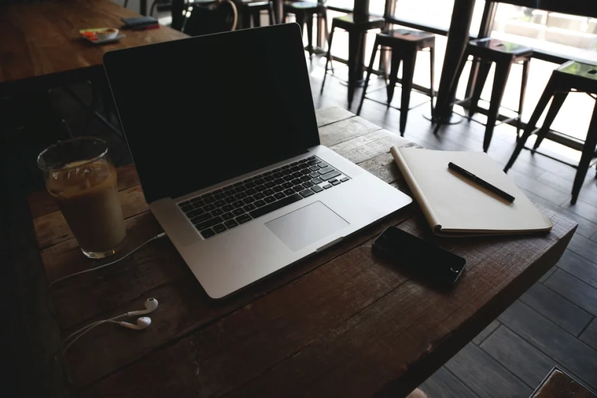Laptop, notebook and iced coffee on a wooden table in a quiet cafe