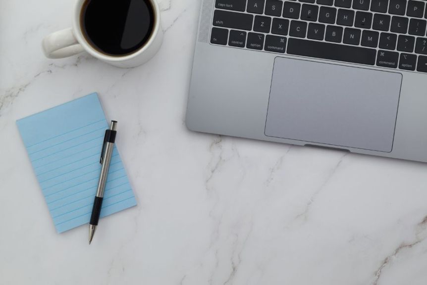 Laptop, coffee cup and notepad on a marble desk