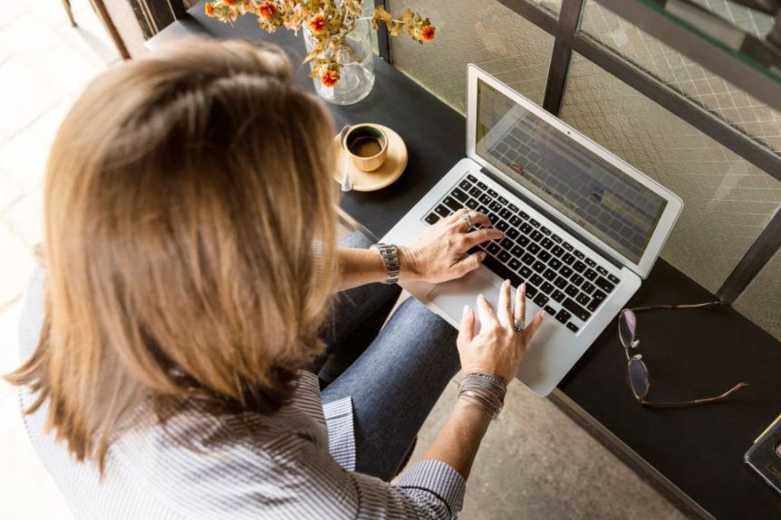 Person typing on a laptop at a desk next to a cup of coffee