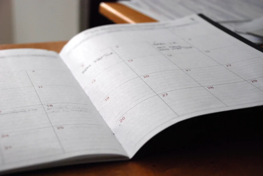 An open monthly planner with handwritten notes on a desk