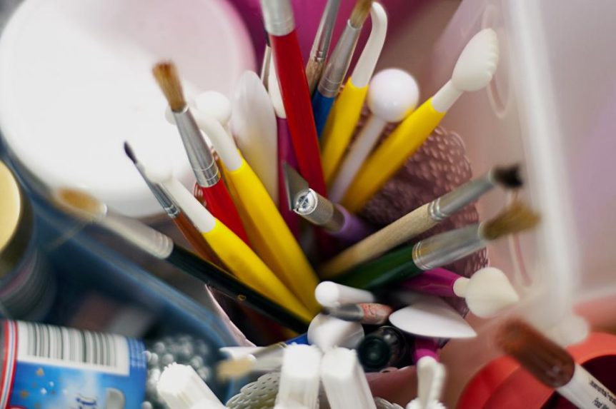 Colorful paint brushes and art supplies in a cup