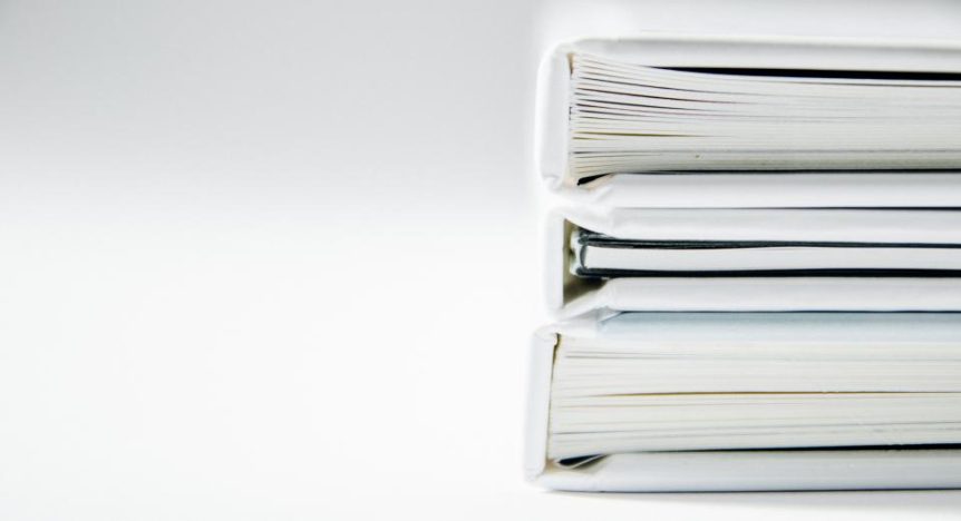 A neat stack of white books and binders on a light background