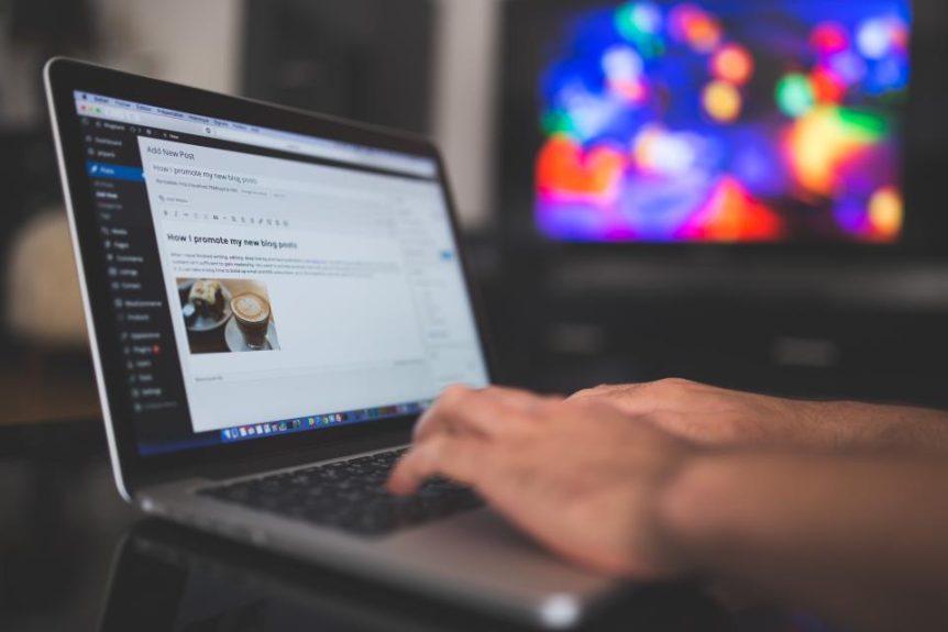 Hands typing a blog post in a WordPress editor on a laptop