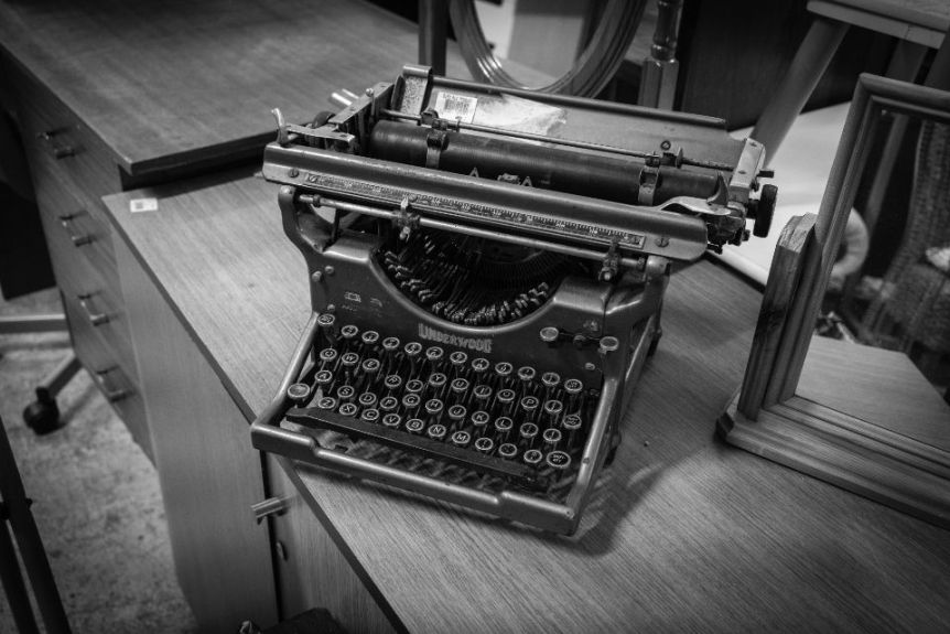 Black and white photo of a vintage typewriter on a wooden desk
